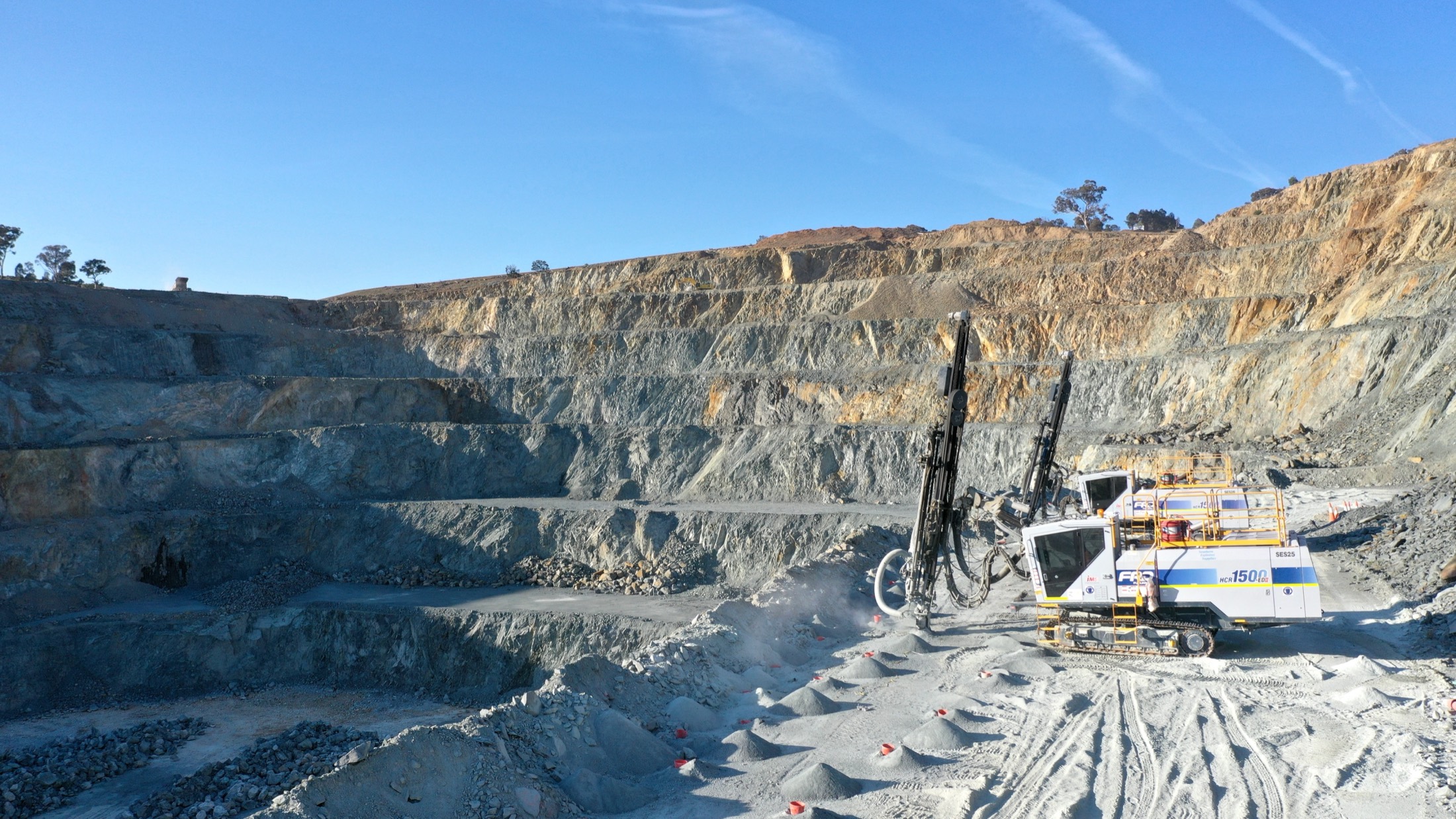 Drill rigs working a high bench in an open quarry