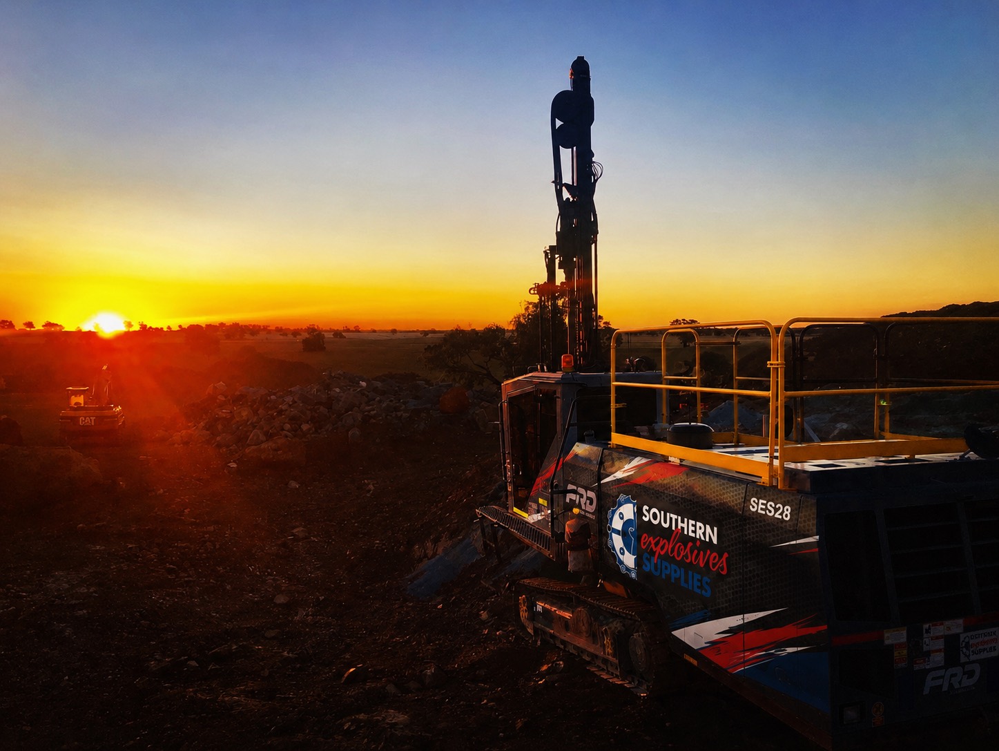 Drill rig operator's machine lit up at sunset