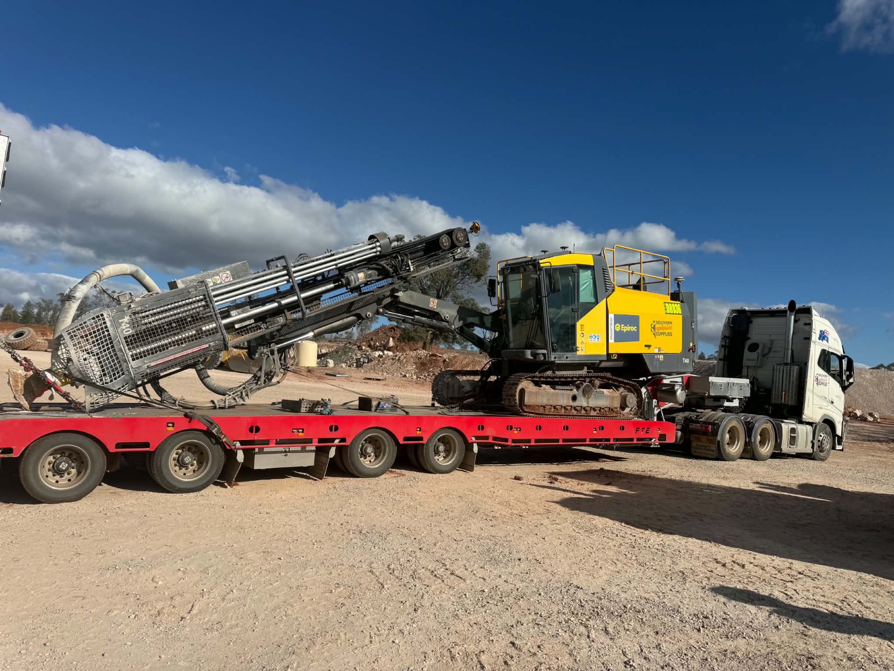 An Epiroc drill rig loaded on a red float trailer ready for transport