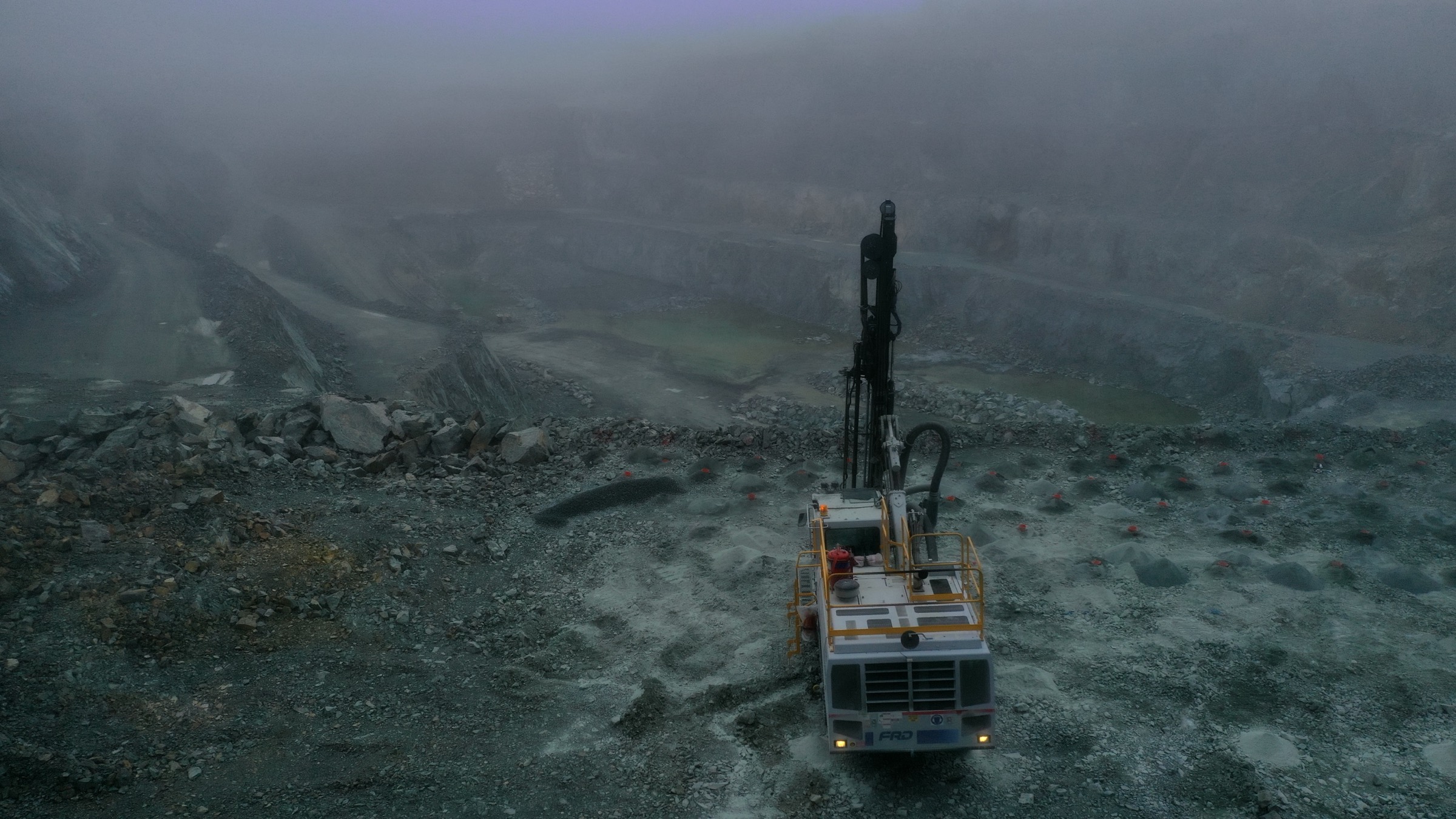 Drill rig overlooking a fog covered open pit at dawn