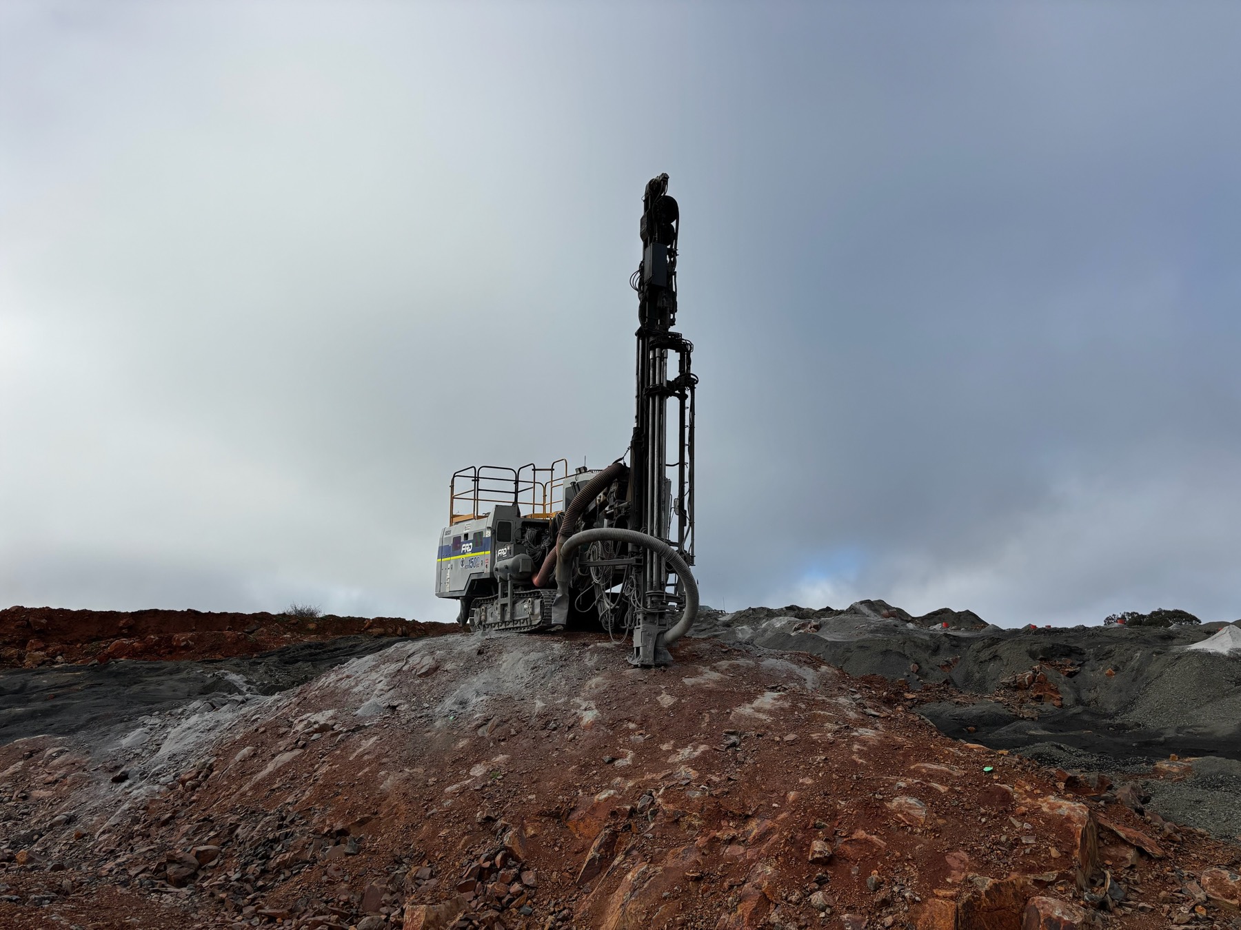 Drill rig with mast raised working on a rocky ridge line