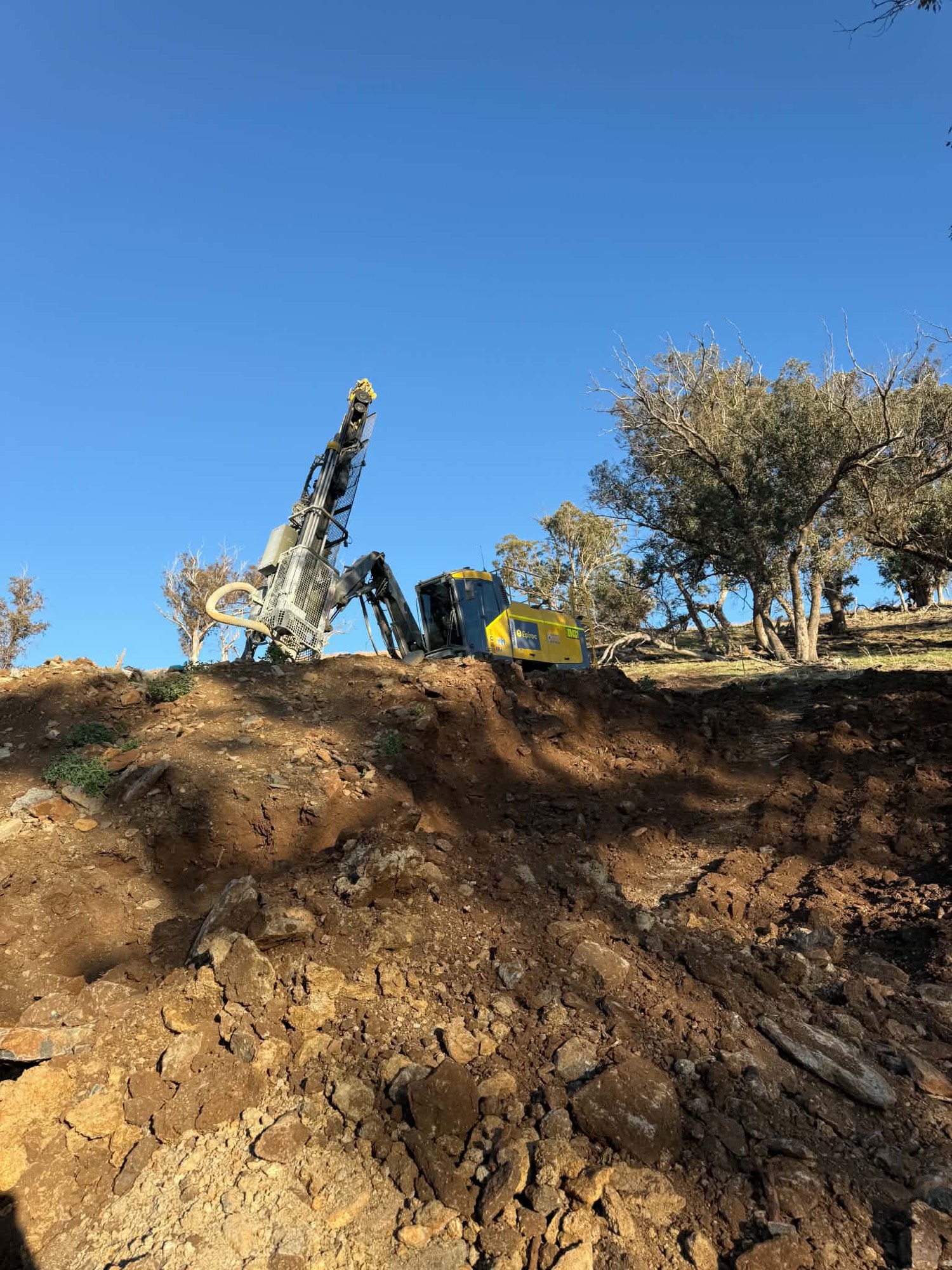 Two drill rigs working a bench at dawn
