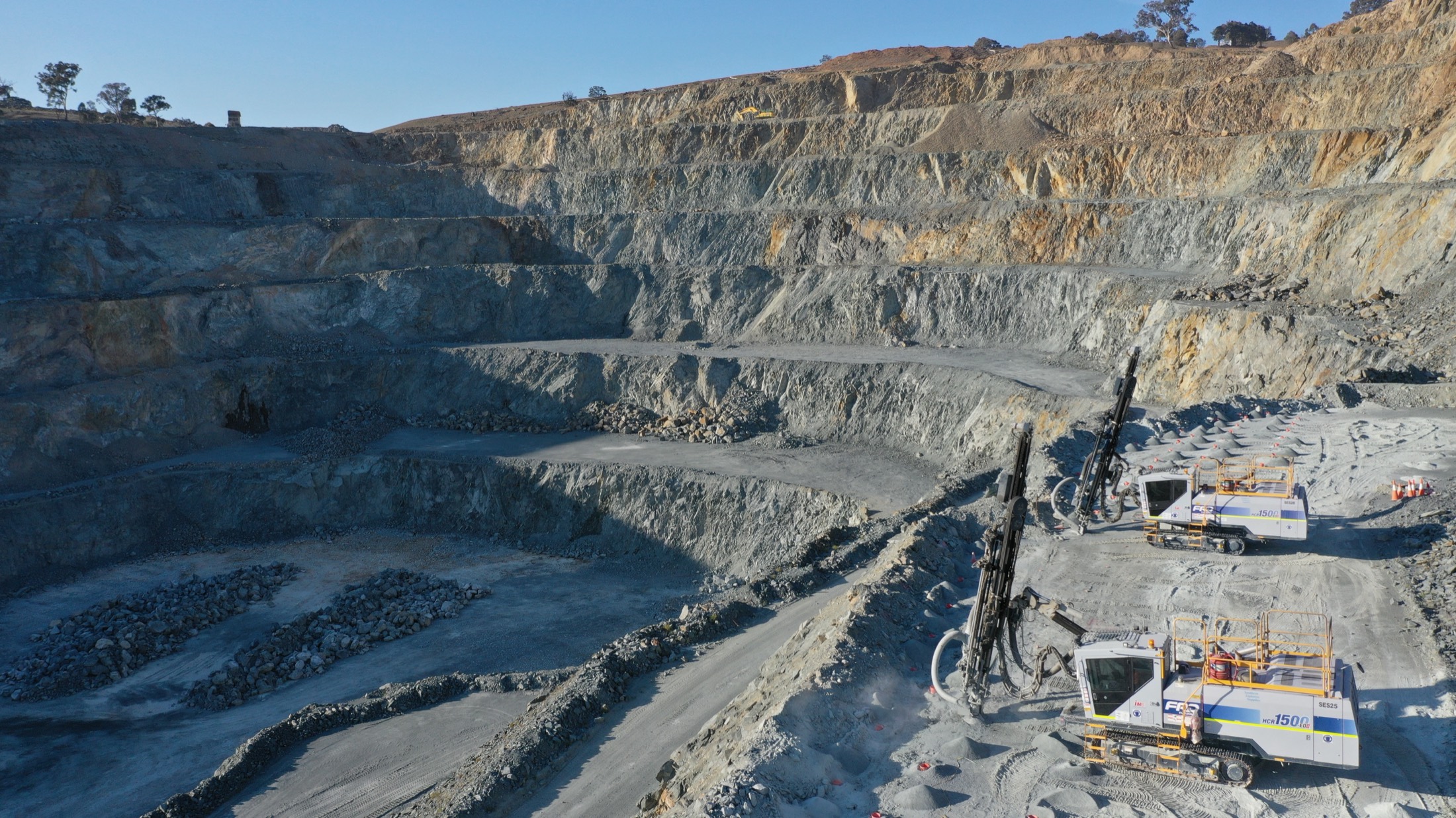 Drill rigs working a bench high on a quarry wall